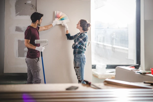 Young couple choosing the right color for their wall while renovating apartment.